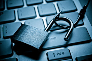 A padlock being pulled away by a fishing hook, on top of a laptop keyboard