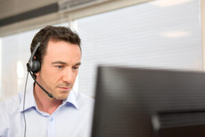 IT support specialist wearing a headset providing remote technical assistance from his desk